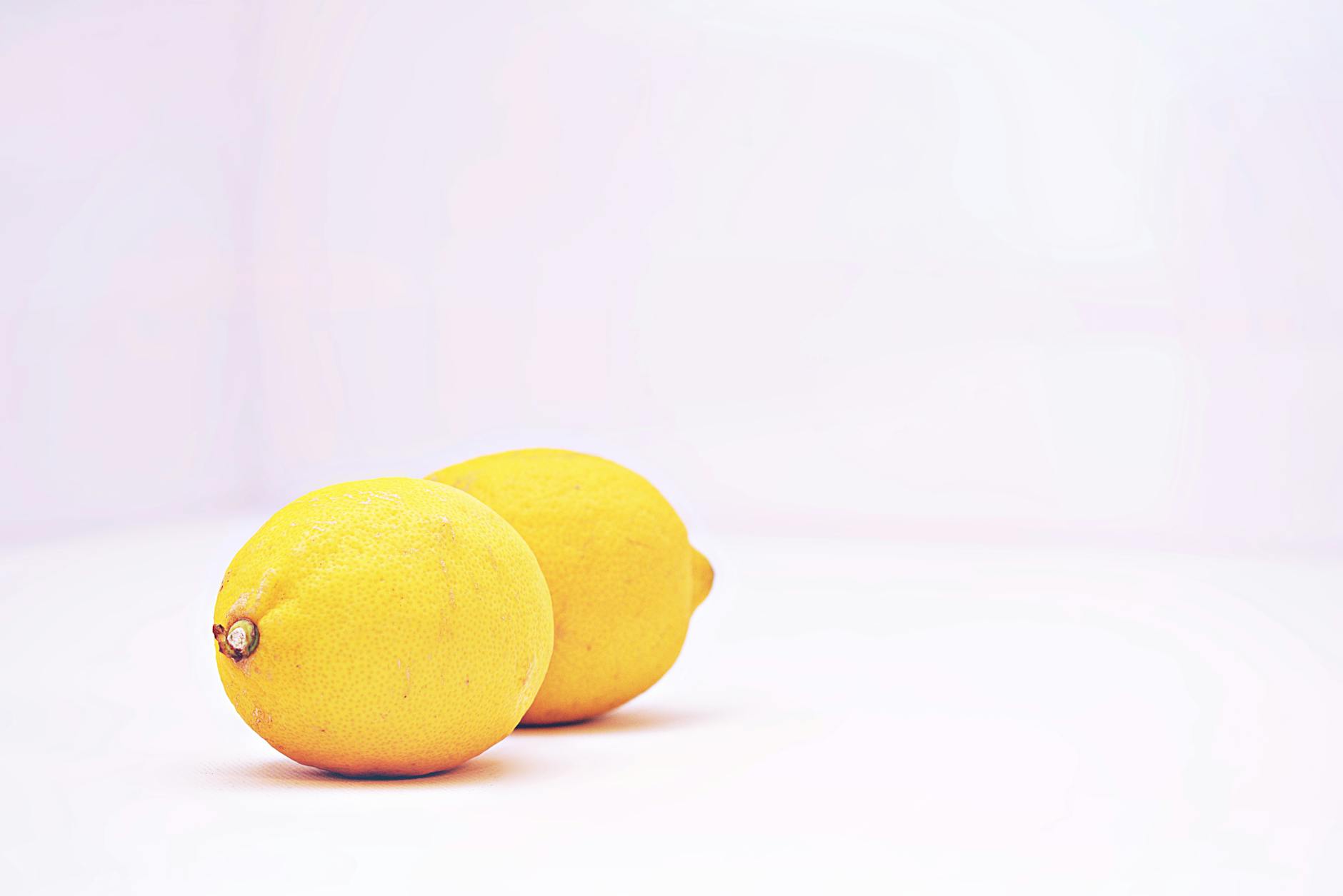 Hand holding a yellow clitoral vibrator against a minimalist purple background