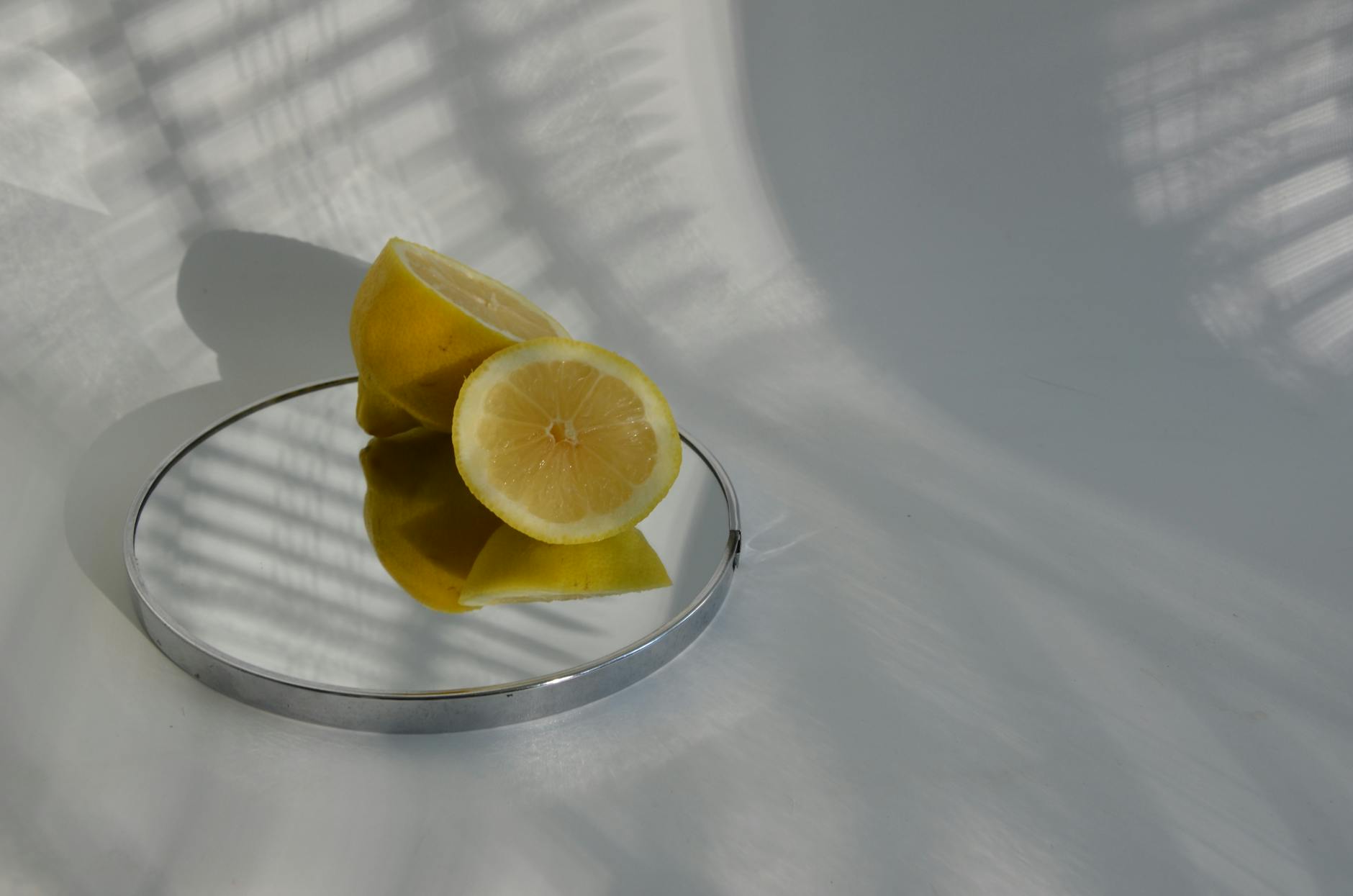 Sliced lemons on mirror with shadows cast by sunlight