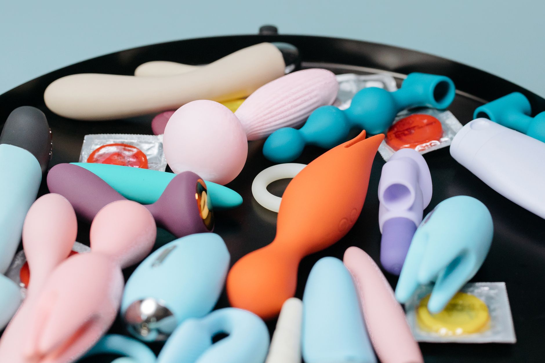 Colorful vibrators and adult toys arranged together on a black surface