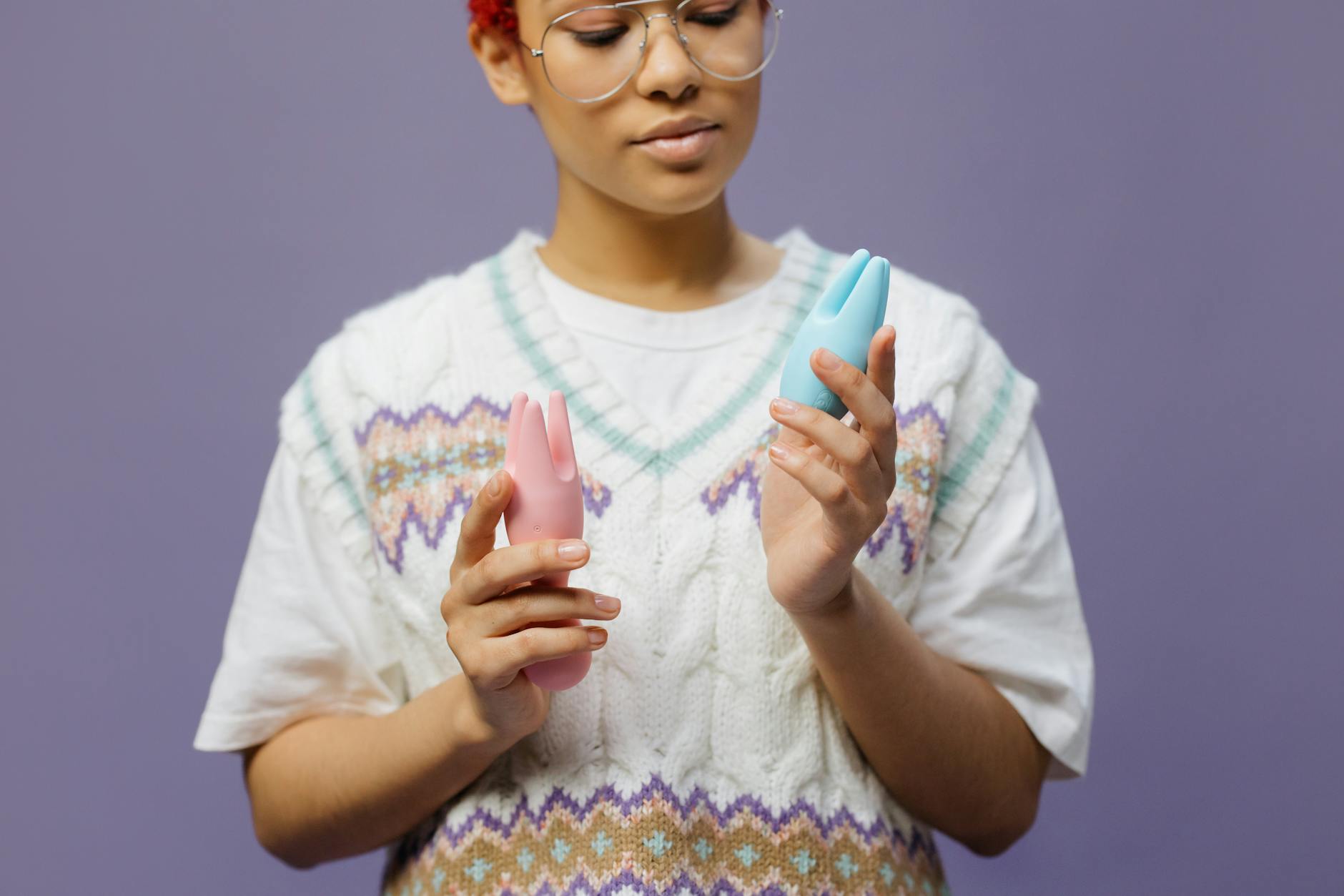 Femme tenant des vibromasseurs rose et bleu dans une posture contemplative