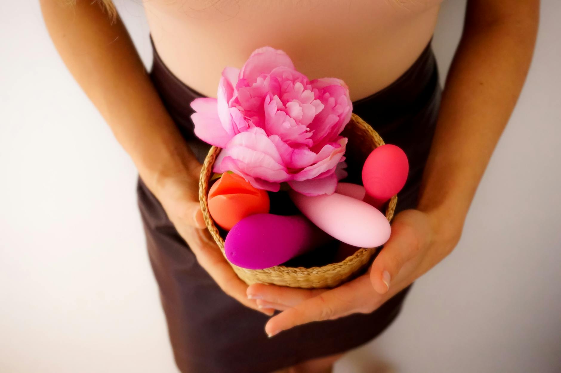 Panier contenant divers vibromasseurs colorés et une fleur rose